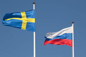 State flags of the Russian Federation and Sweden on the background of blue sky