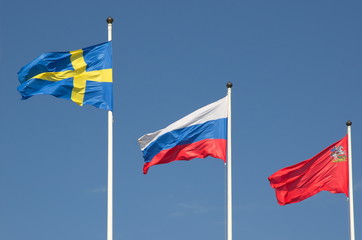 State flags of the Russian Federation, Sweden and Moscow region on the background of blue sky