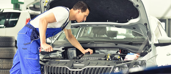 Mechaniker repariert defektes Fahrzeug in einer Autowerkstatt // car mechanic repairs vehicle in...