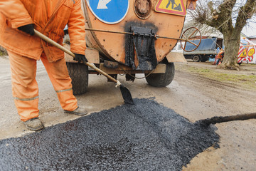 Workers repairing the road with shovels fill asphalt driveway repair