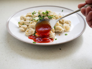 Pouring ketchup over meat dumplings.