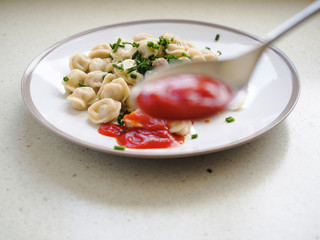 Plate with meat dumplings in focus, spoon with ketchup in front out of focus.
