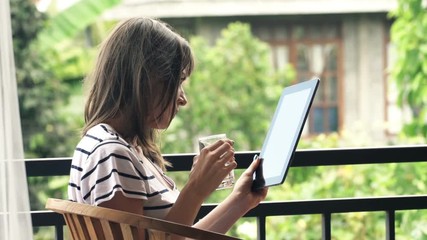 Young woman reading news on tablet and drinking water on terrace
- Powered by Adobe