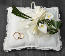 Wedding rings with calla bouquet on bridal pillow