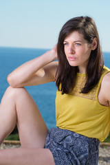 Portrait of beautiful young woman relaxing in sun with sea in ba