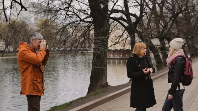 Adult man photographer take pictures of a woman and girl with old vintage film camera