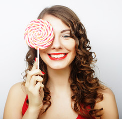 smiling cute girl covering her eye with lollipop over white back