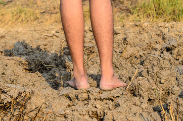Barefoot standing on dry and cracked ground,barren ground