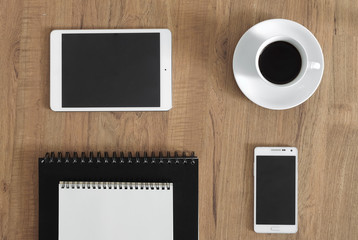 Digital tablet, smartphone, notebook and coffee on the wooden de