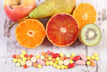 Fresh fruits and colorful medical pills, choice between healthy nutrition and medical supplements