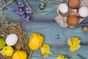 Easter eggs, flowers and other decorations over blue wooden table.