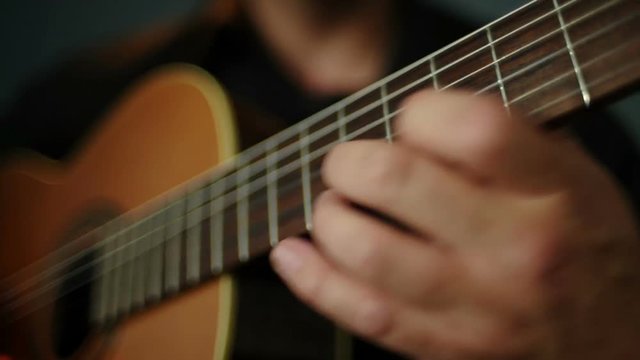 A man plays the guitar chords changing fingers