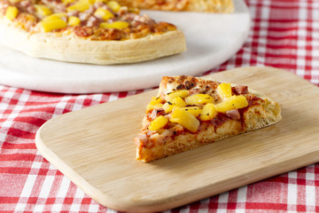 hawaiian pizza on a wooden plate