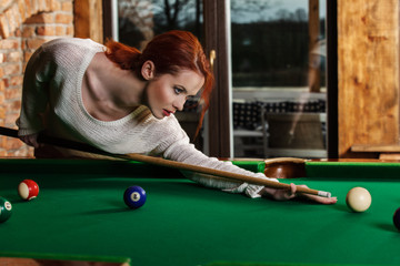 Attractive woman plays the game of snooker pool table