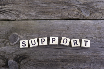 Text: Support from wooden letters on wooden background