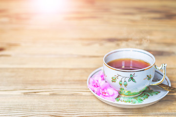 Cup of hot fresh tea on a wooden table.