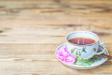Cup of hot fresh tea on a wooden table.