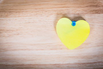 Heart pin on wooden wall background texture.
