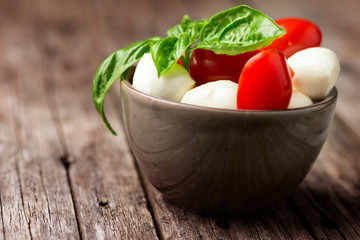 Tomato and mozzarella with basil leaves in bowl