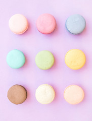 Sweet colorful French macaroon biscuits on pastel lilac background
