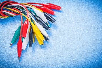 Assortment of electric crocodile clip cables on blue background 