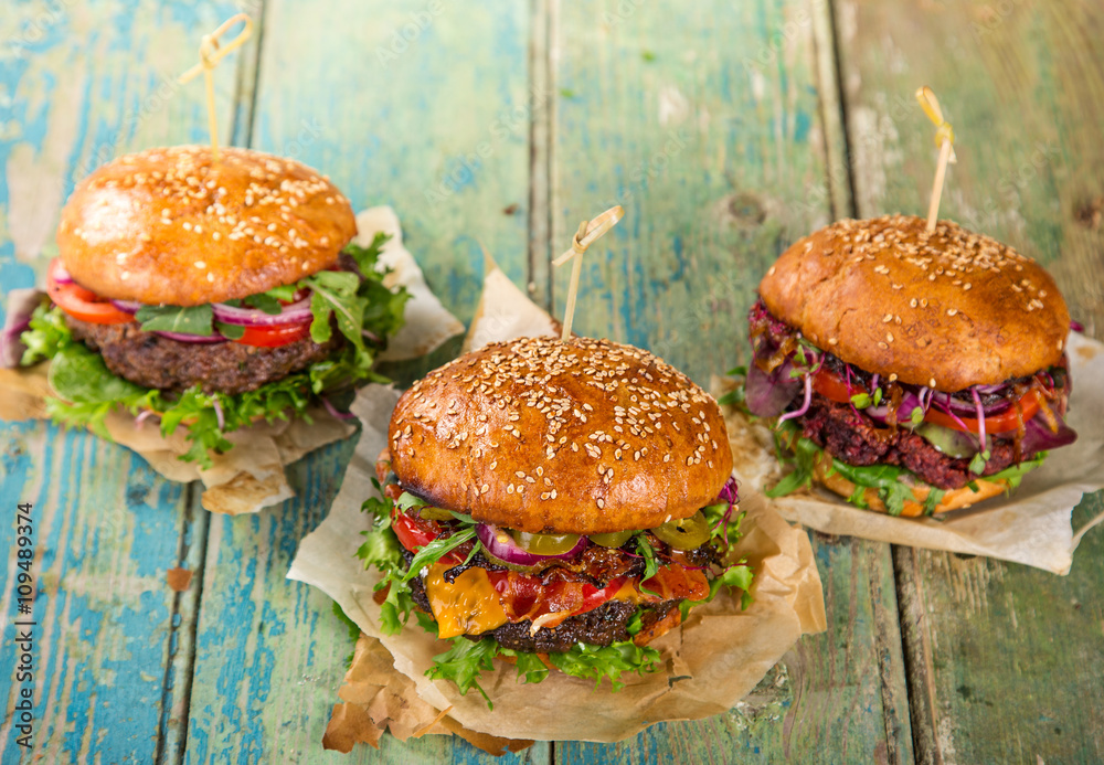 Wall mural tasty burgers on wooden table.