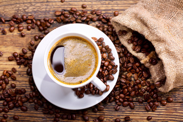 cup of coffee with beans on wooden table