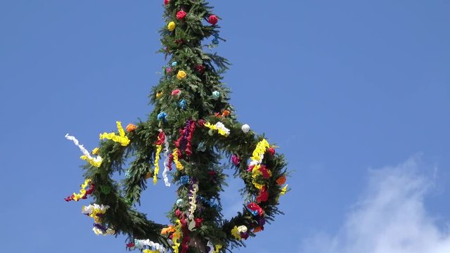 Maibaum mit bunten B&auml;ndern vor blauem Himmel