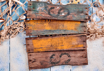 Old wooden blank sign over sand and fishing net