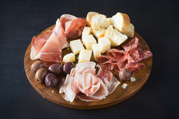 Traditional italian plate with  prosciutto crudo, salami, parmesan cheese, olives and bread. Selective focus.