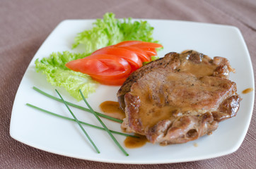 Decorated pork steak plate with slices of tomato