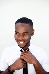 Happy young black businessman adjusting his necktie