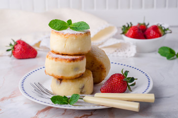 Fritters of cottage cheese with strawberries, sugar powder and mint on wooden background. Selective focus