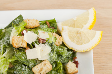 a plate with caesar salad and slice lemon side dish