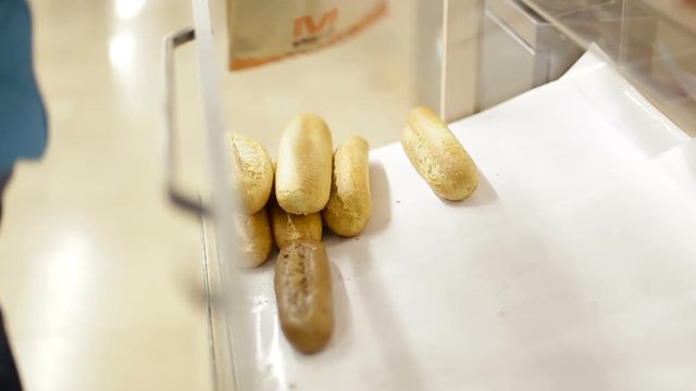 Female hand taking a loaf of bread tongs adds to the package at the supermarket