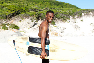 Smiing young african man at beach with surfboard