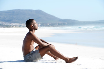 Young african man sitting alone on the beach