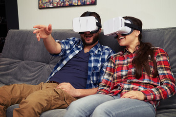 Couple in virtual reality glasses discussing something at home