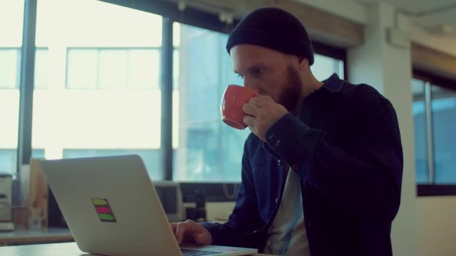 Man drinks coffee while working in the startup office
