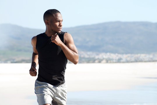 Handsome young african american man running on the beach