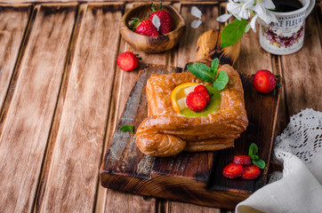 Freshly baked puff pastry with fruits and strawberries on wooden background. Selective focus. Top view