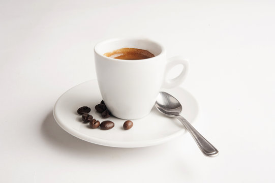 Cup of coffee on white background with spoon and coffee beans