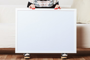 woman on sofa holding blank presentation board.
