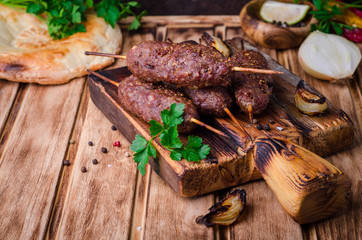 Roasted kebab skewer with spices on cutting board and wooden background. Selective focus