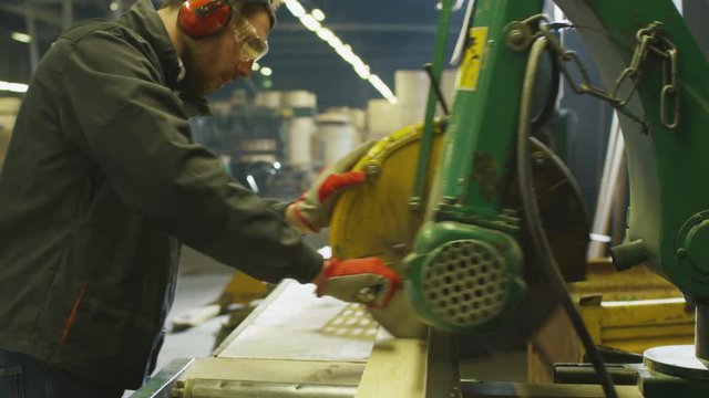 Lumber mill worker is cutting wood with circular saw. Shot on RED Cinema Camera.