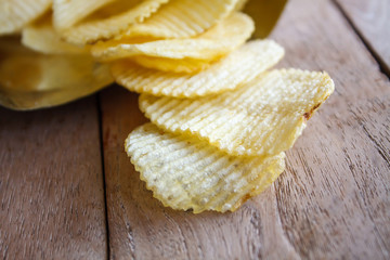Opened pack with potato chips over wooden table