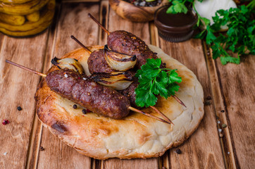 Roasted kebab skewer with spices on flatbread  and wooden background. Selective focus
