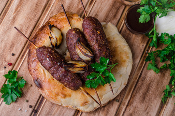 Roasted kebab skewer with spices on flatbread  and wooden background. Selective focus