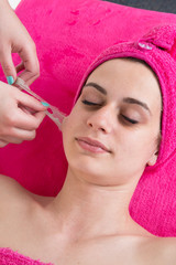 Woman relaxing and removing facial peel off mask on gray. Peeling