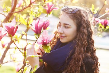 Spring portrait of a beautiful woman smelling magnolia flower